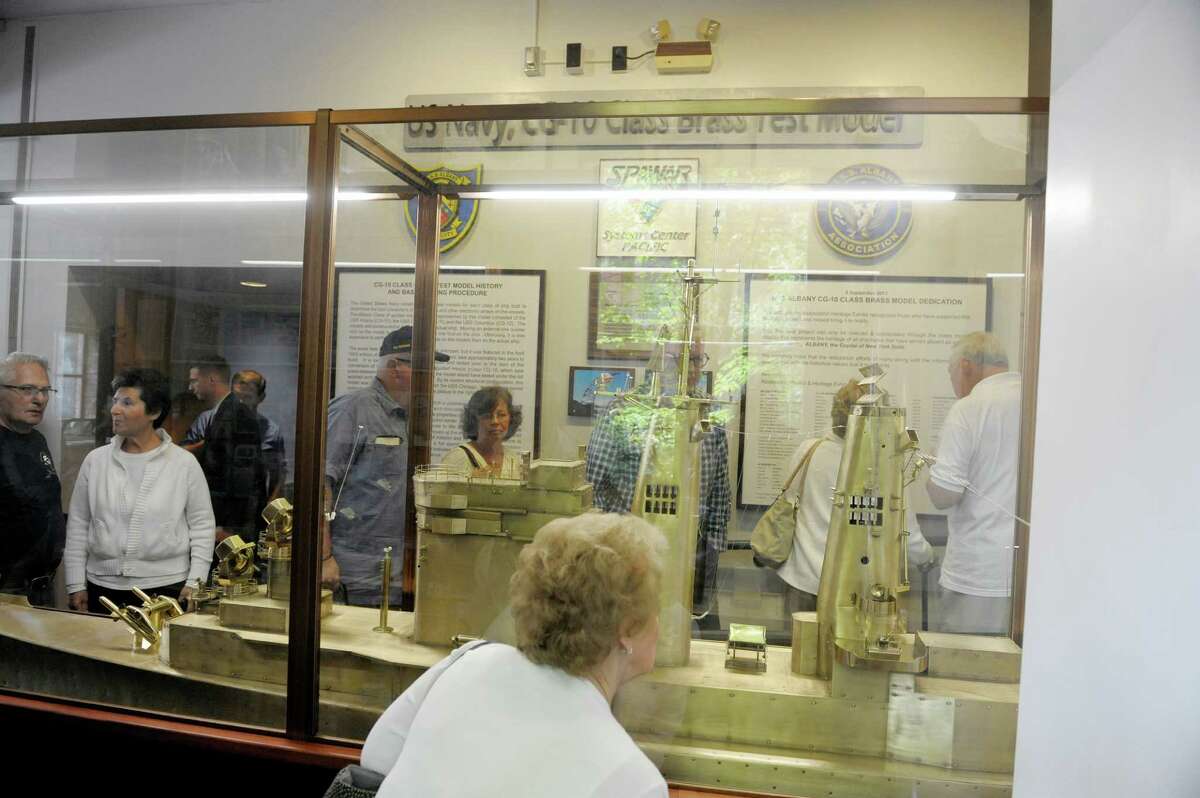 Visitors look over the brass model of the USS Albany at the opening of a new permanent exhibit at the Albany Heritage Area Visitors Center on Monday, Sept. 9, 2013 in Albany, NY. The exhibit is the current USS Albany submarine and memorabilia from the USS Albany CG-class guided missile cruiser. The Navy constructs brass test models for a class of ship to determine the placement of the antenna and electronic arrays on the vessel. The models are 1/48 scale. (Paul Buckowski / Times Union)