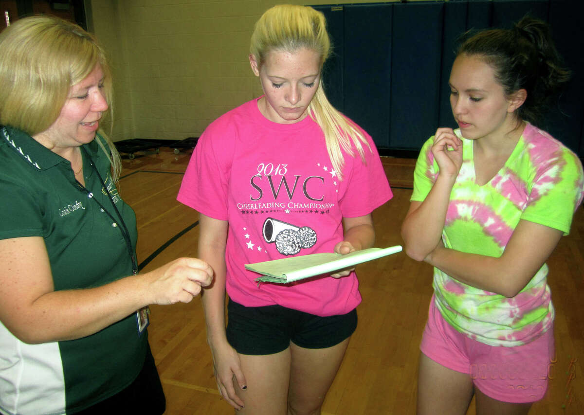 Green Wave captains Janna Stratman, center, and Meghan Timan lend counsel to coach Cindy Dubret's team strategy during pre-season for New Milford High School cheerleading. September 2013