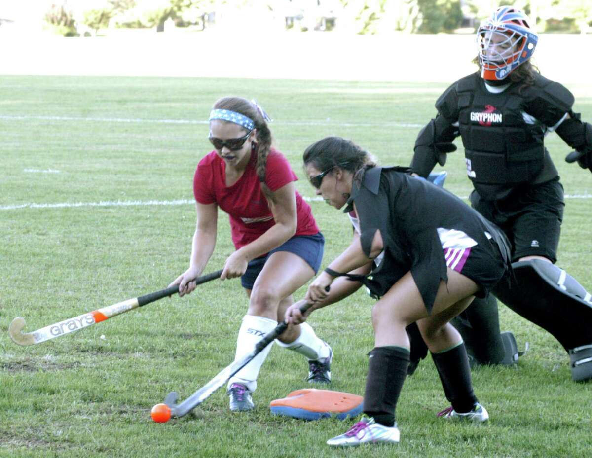 Green Wave metminder Denise Landry stands ready for a possible save as teammates Ashley Maioriello, left, and Nicoleta Ceconi battle for the ball during a pre-season scrimmage for New Milford High School field hockey, September 2013