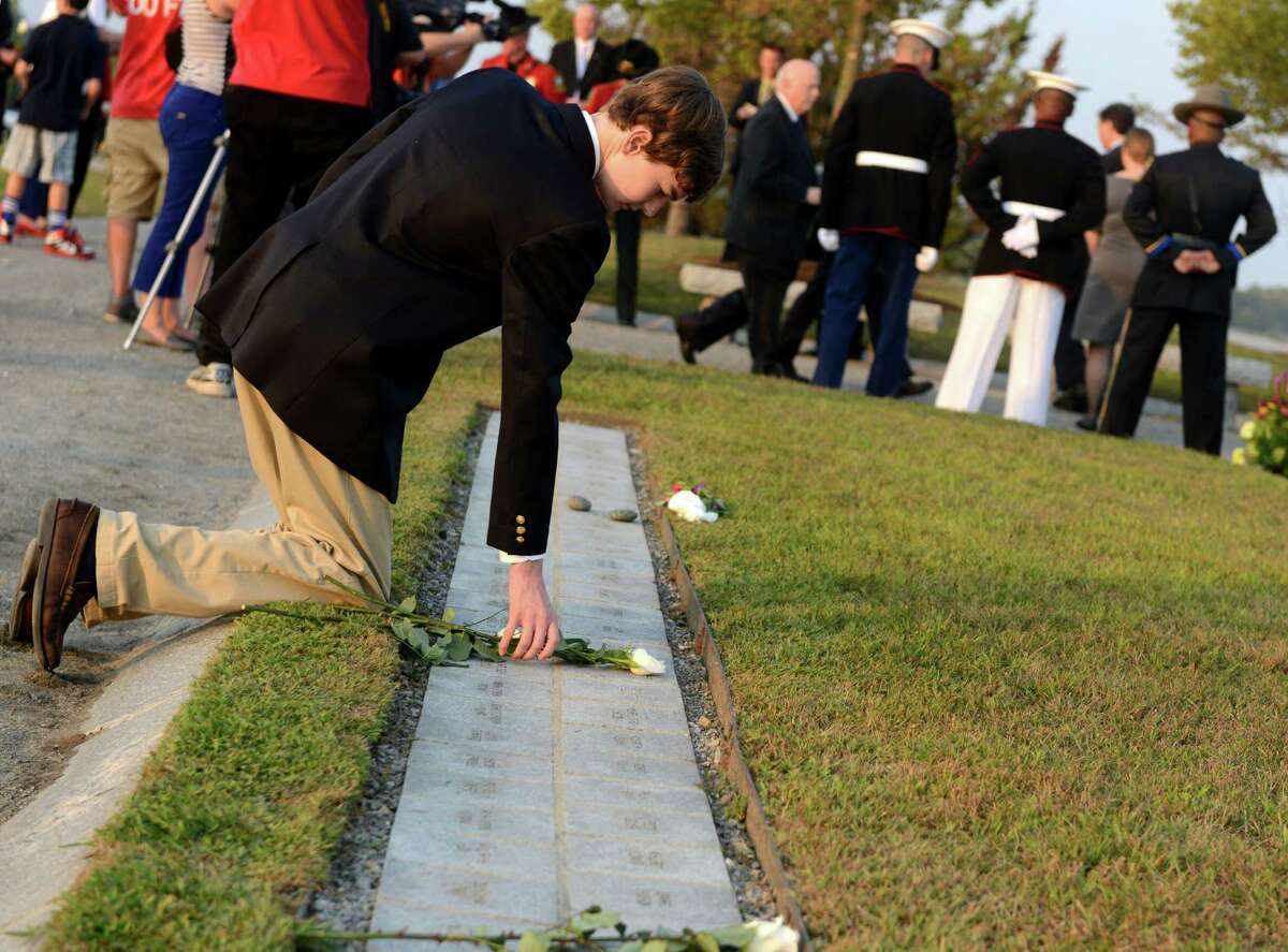 Christopher Gardner, 15, of Darien, places a flower on his father's memorial stone at Connecticut's 9/11 Living Memorial during the annual 9/11 Memorial Service Tuesday, September 10, 2013 at Sherwood Island State Park in Westport, Conn. His father, Christopher Samuel Gardner, worked at the World trade center and died on 9/11.