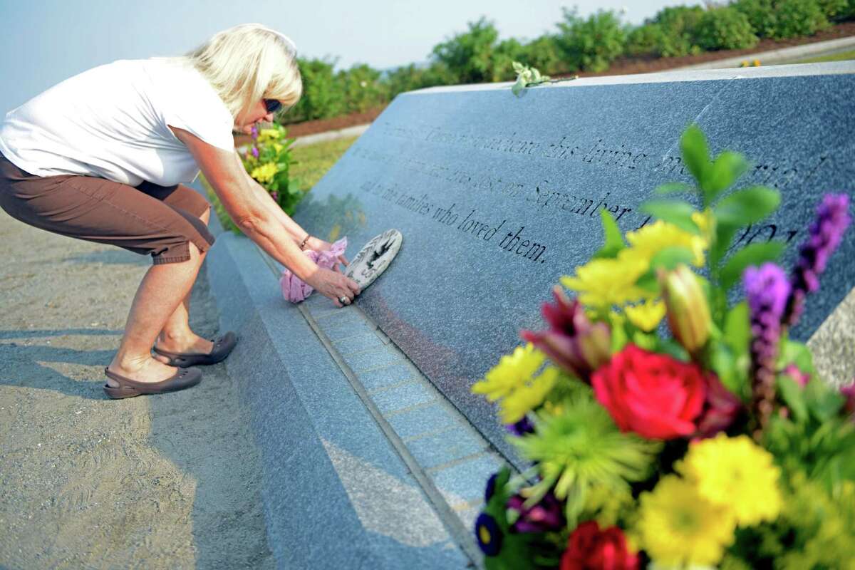 Monica Schaefer, of Bethel, places a "peace" plaque on Connecticut's 9/11 Living Memorial before the annual 9/11 Memorial Service Tuesday, September 10, 2013 at Sherwood Island State Park in Westport, Conn. Schaefer's childhood friend died on 9/11.