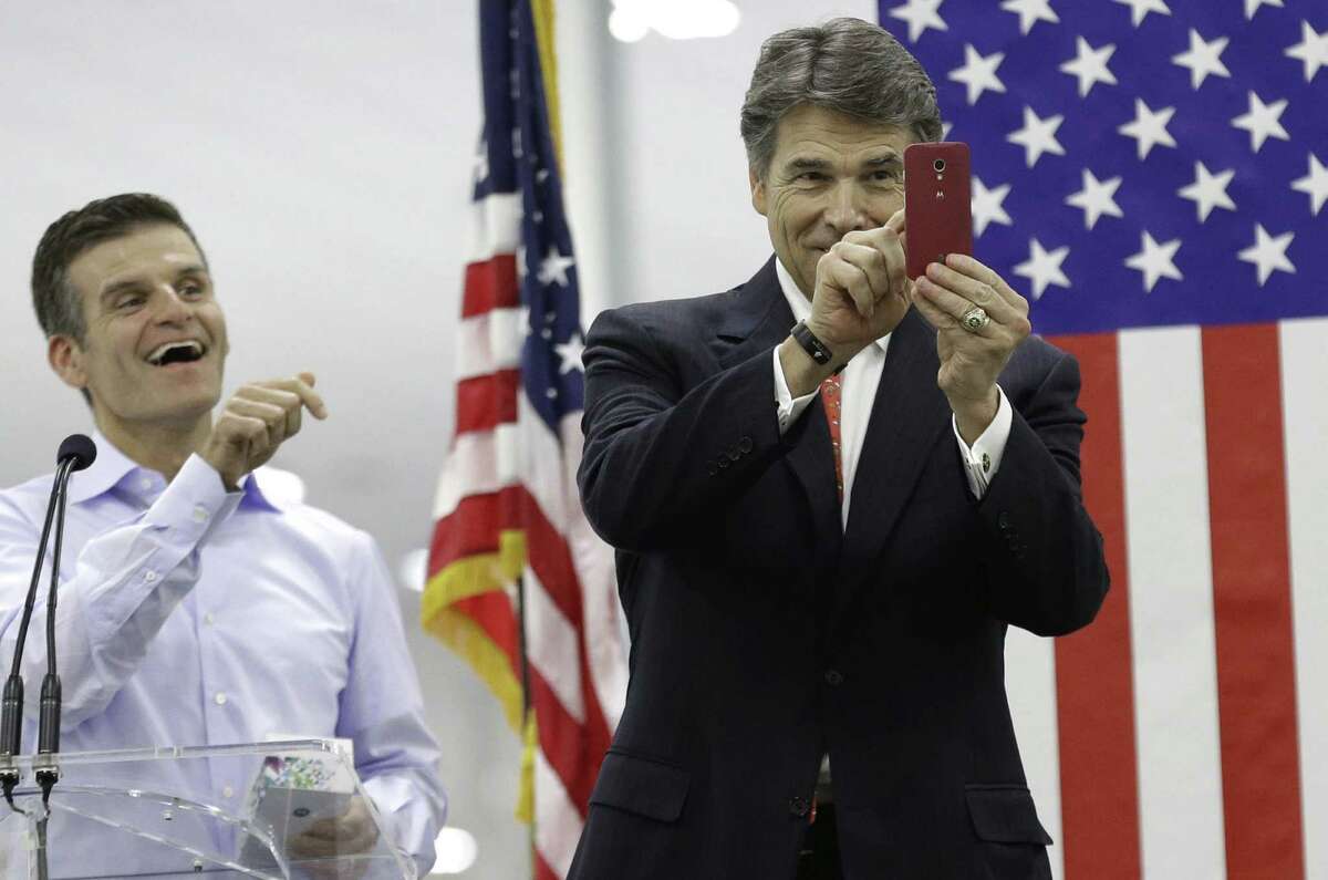 Motorola CEO Dennis Woodside (left) laughs Tuesday as Gov. Rick Perry uses a smartphone given to him during the opening ceremony for a Motorola factory in Fort Worth.