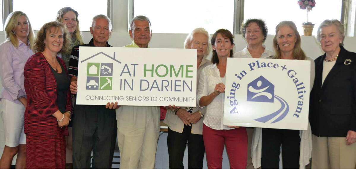 Members of the board of directors of At Home in Darien display the new and previous logo designs for the agency. From left, Maureen Tyrrell, Gina Blum, Erin Shea, Peter Eder, Bill Ball, Kaye Barker, Anne McGuire, Amy Squyres, Nancy Herling and Diana Kalman.