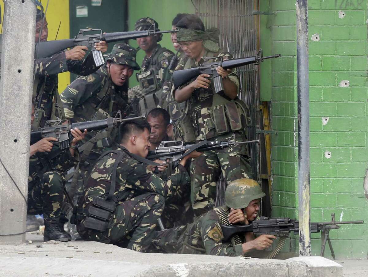 Government troopers fire their weapons as they continue their assault on Muslim rebels Thursday in Zamboanga, a city in the southern Philippines. Extremists attacked a second city near the southern port where guerrillas have been holding scores of residents hostage in a four-day standoff.
