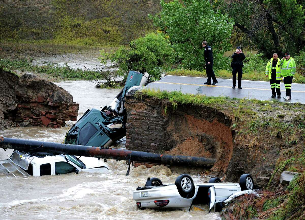 Officials investigate the scene of a road collapse at Highway 287 and Dillon at the border of Broomfield and Lafayette, Colo., that sent three vehicles into the water after flash flooding on Thursday. The National Weather Service warned of an “extremely dangerous and life- threatening situation” throughout the region.