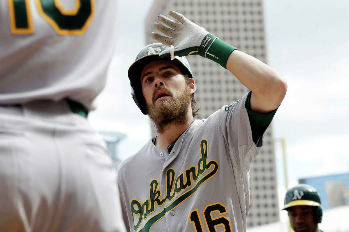 Oakland Athletics' Josh Reddick (16) is welcomed at the dugout by Daric Barton after hitting a two-run home run off Minnesota Twins pitcher Brian Duensing in the eighth inning of a baseball game on Thursday, Sept. 12, 2013 in Minneapolis. The Athletics won 8-2. (AP Photo/Jim Mone)