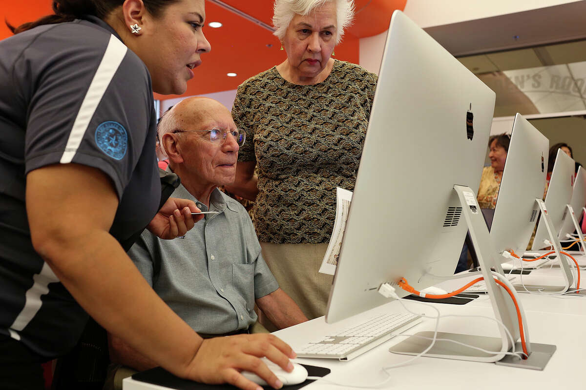 Maria Elena Martinez, Library Technical Assistant, left, helps Heron Pena, with his wife, Alice Yturri Pena, figure out his password to use his library card during the grand opening of BiblioTech, the first Bexar County Digital Library, in San Antonio on Saturday, September 14, 2013.