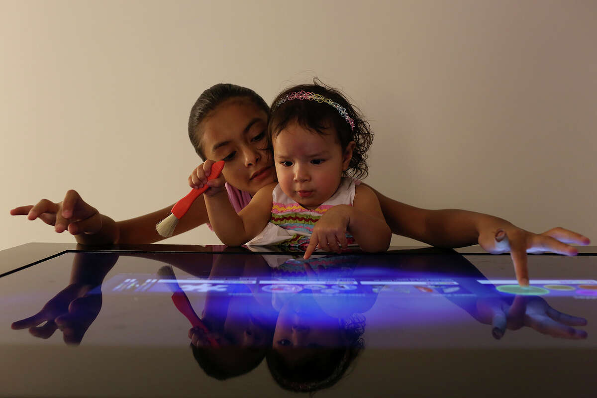 Belen Mendoza, 10, and her sister, Viviana Fierro, 1, play a Kaplan touch screen game during the grand opening of BiblioTech, the first Bexar County Digital Library, in San Antonio on Saturday, September 14, 2013.