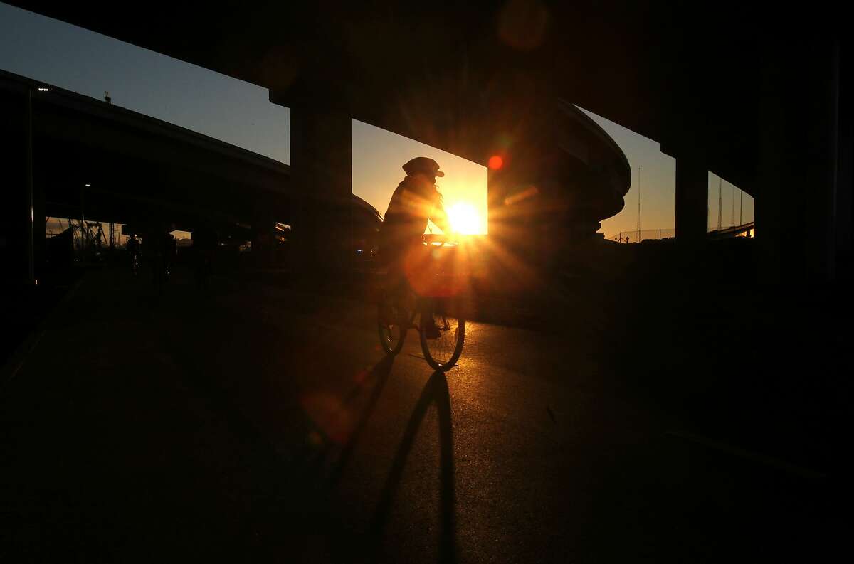 A cyclist rides under an over pass as the sun sets September 14, 2013 on the new Bay Bridge bike path in Oakland.