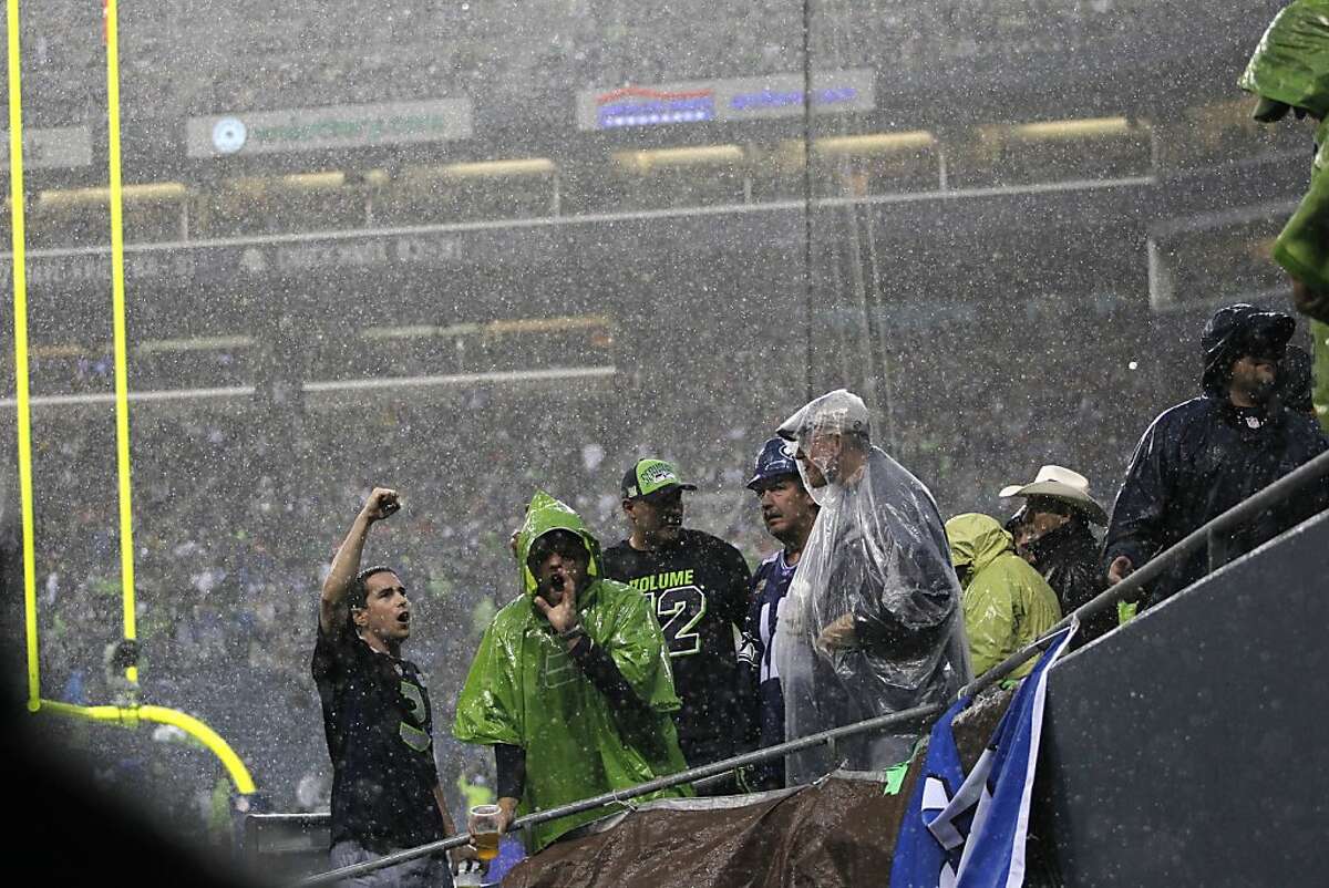 Seattle Seahawks fans cheer as rain pours down during a severe weather delay in the first half of an NFL football game between the Seattle Seahawks and the San Francisco 49ers, Sunday, Sept. 15, 2013, in Seattle. (AP Photo/John Froschauer)