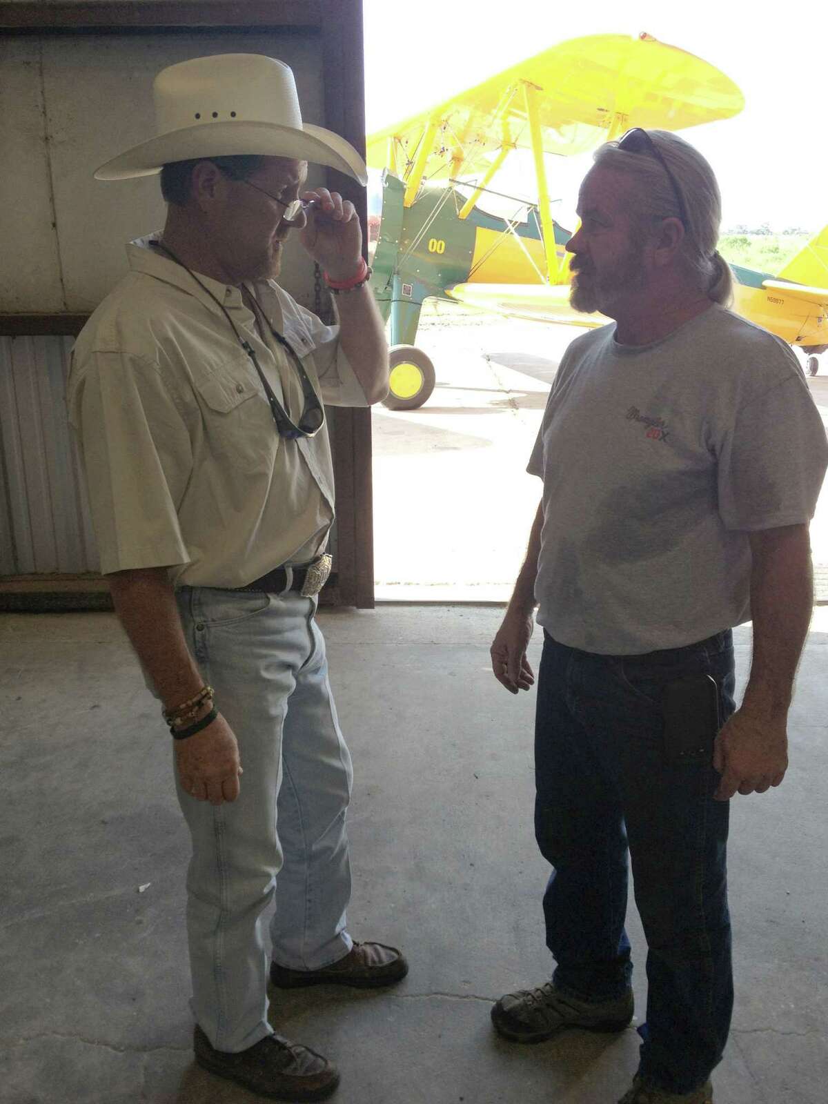 David Mitchell, left, talks with mechanic Brad CAlloway about a new distribution system being installed in their planes. In the background is a Stearman plane, one of the first planes used by the company to seed Southeast Texas' rice fields by air.