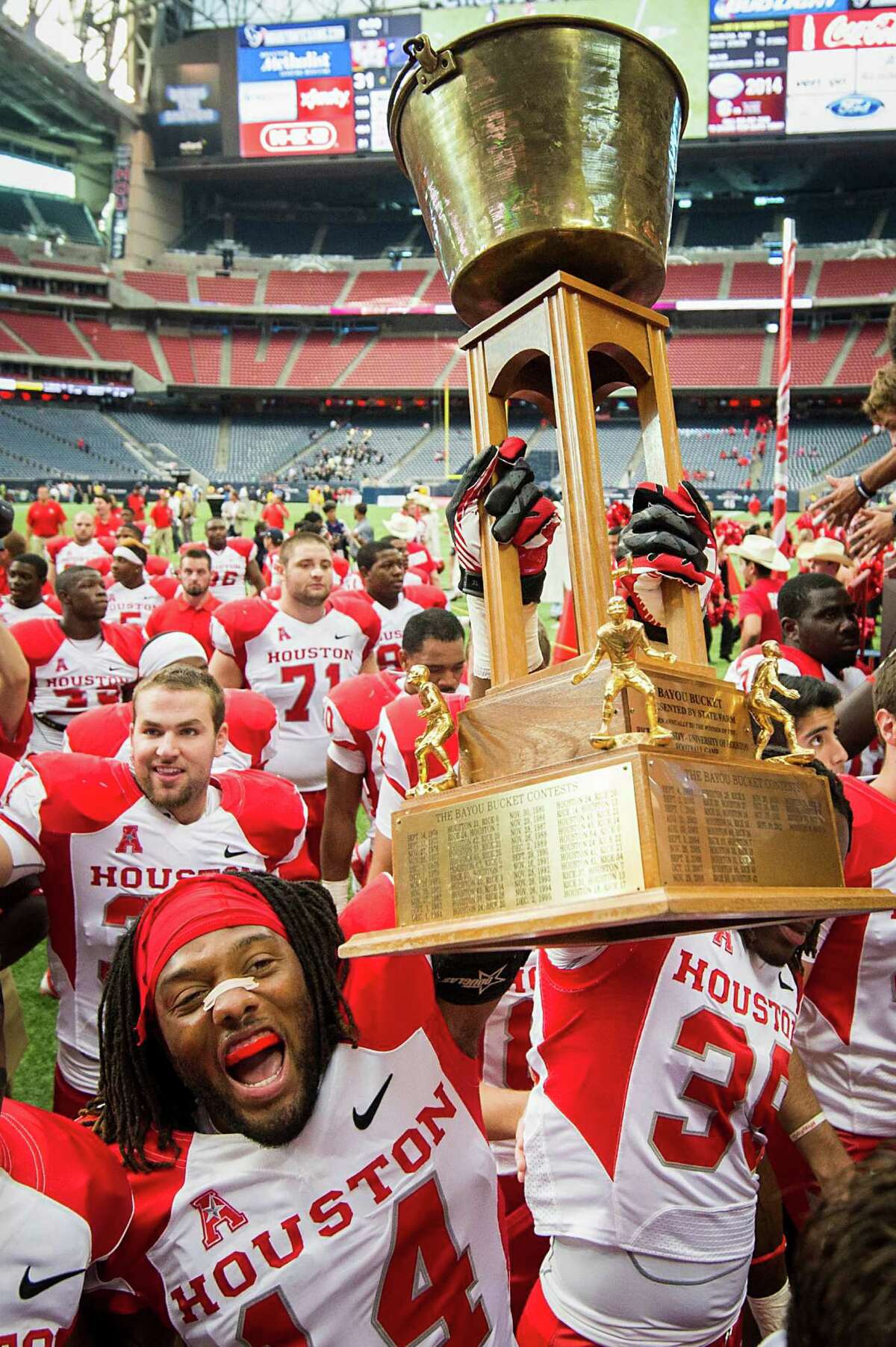 Houston defensive backs Jarrett Irving (14) and Steven Aikens (39) carry the Bayou Bucket off the Reliant Stadium field after beating Rice and claiming the trophy for the third consecutive year.