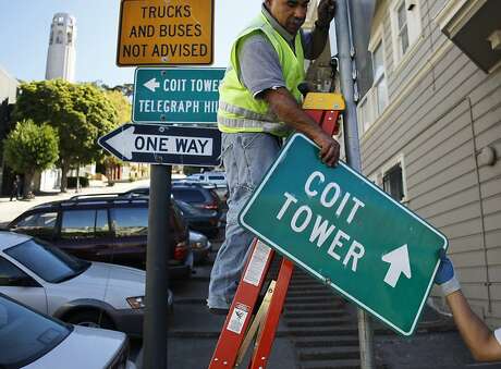Rick Collaco, right, hands a sign to Mario Mendieta at the corner of Filbert Street and Grant Avenue on September 18, 2013 in the Telegraph Hill area of San Francisco, Calif. Collaco and Mendieta, who are both 7457 sign workers, were installing additional signage to the area around Coit Tower.