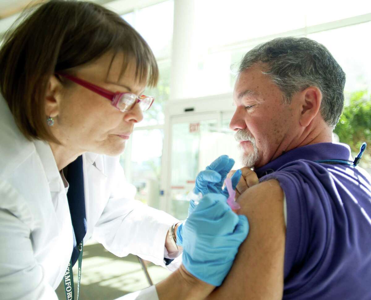 Paul Ginotti gets a flu shot from Sandra Morano at Government Center on Tuesday, Sept. 24, 2013.