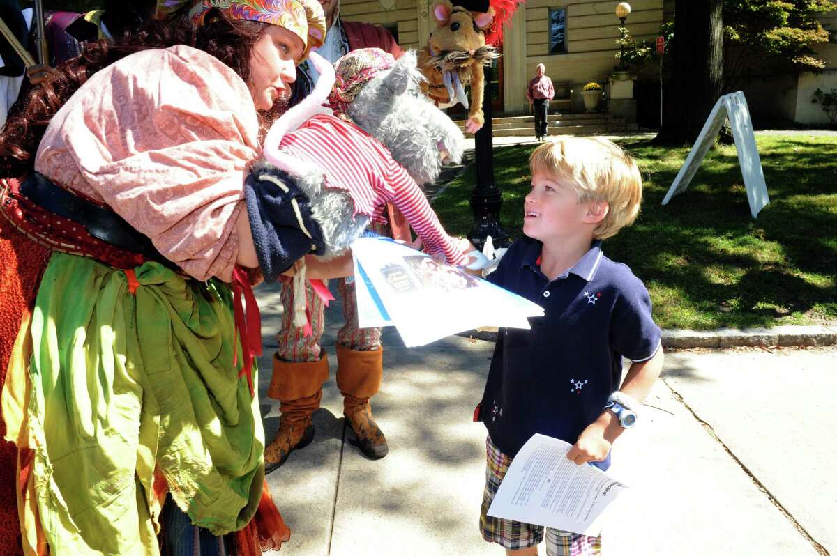 Rene Regan, an actor of Cabaret Children's Theatre, gives Parker Flynn, 6, of Greenwich, information of Children Theatre, strowling down Greenwich Avenue, in Greenwich, Conn., Tuesday, Sept. 24, 2013.