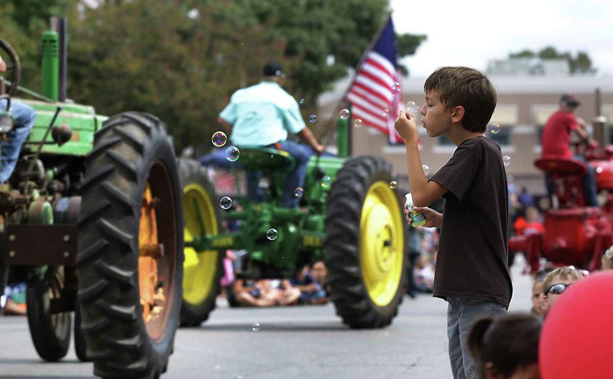 Hunter Fontaine, 9 yr. old, blows bubbles as a long line of tractors roll down San Antonio St. during the Comal County Fair Parade through the center of New Braunfels, on Friday, Sept. 27, 2013.
