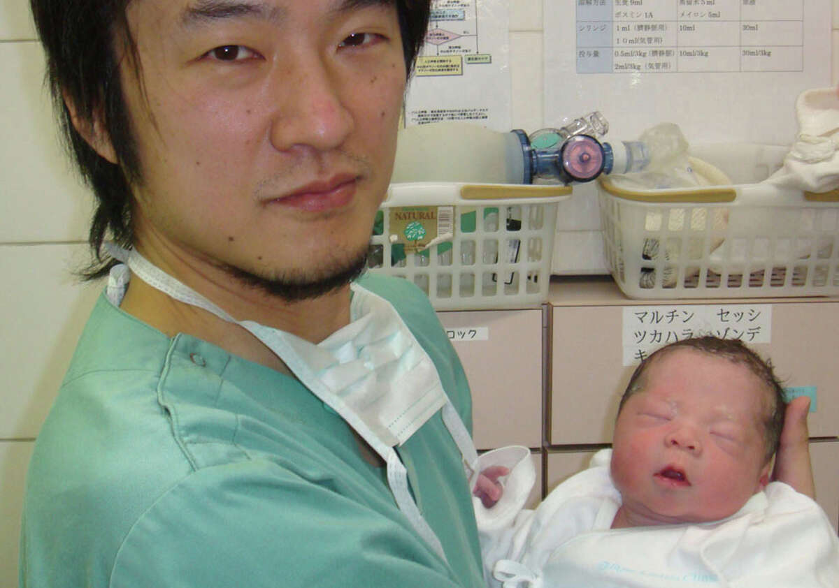 Dr. Kazuhiro Kawamura holds a newborn whose 30-year-old mother was treated for primary ovarian insufficiency, sometimes called premature menopause.