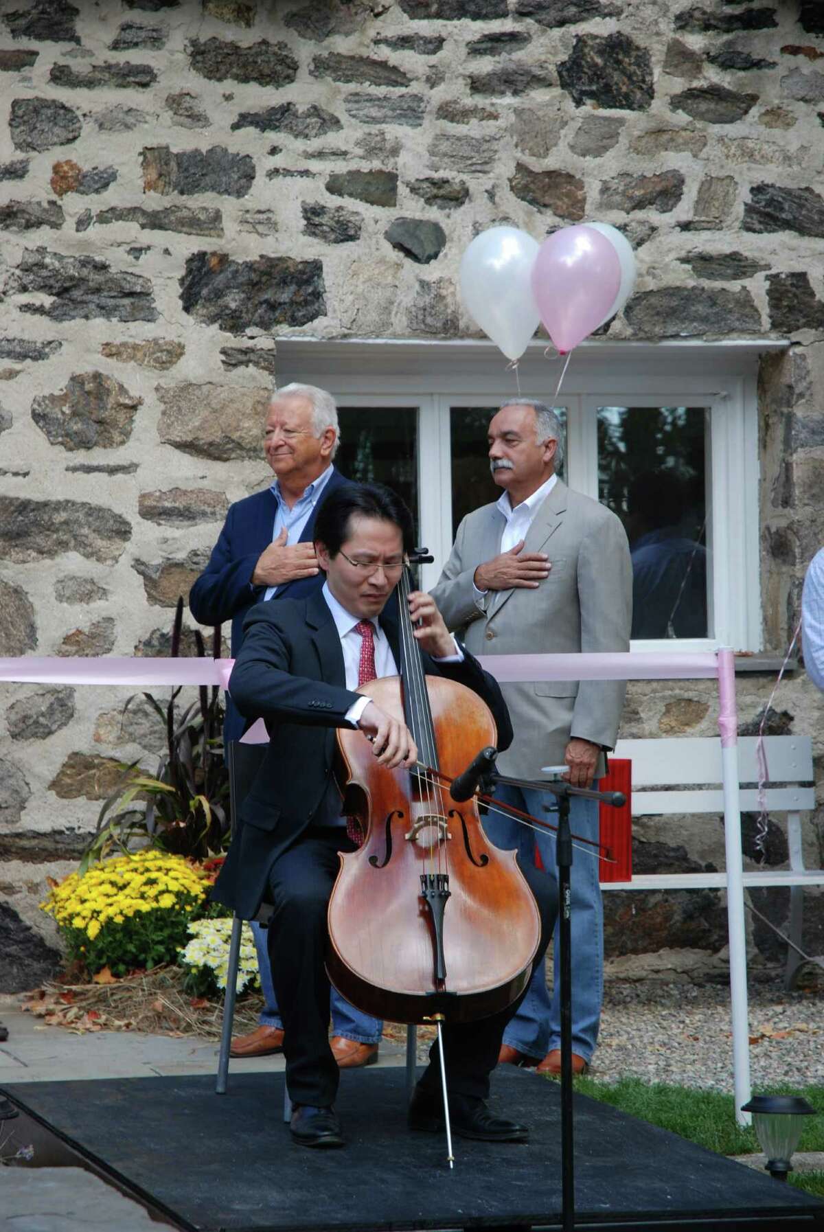 Kenneth Kuo, owner of Rental Instrument, LLC, plays the National Anthem at the establishment's grand opening Sunday as Norwalk Mayor Richard Moccia and superintendent of schools Manny Rivera look on.