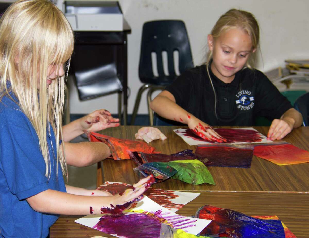 Mackenzie Pettigrew and Paige Huh finger-paint in Lona Dekenipp's second- and third-grade art class at Living Stones Christian School in Alvin.  