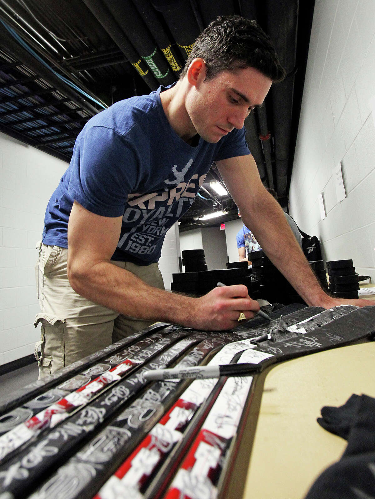 Dov Grumet-Morris autographs hockey sticks as the Rampage hockey team conducts media day at the AT&T Center on October 1, 2013