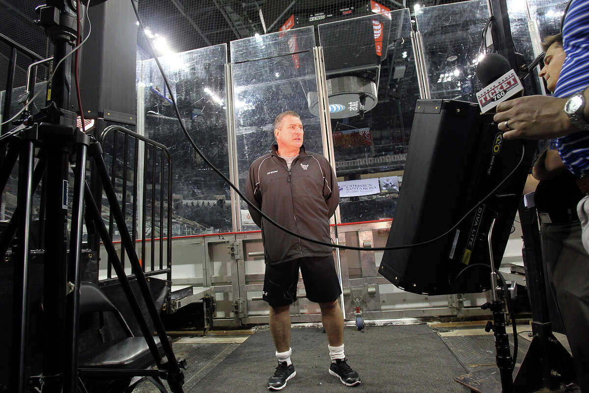 Coach Peter Horachek talks on camera with the ice rink in the background as the Rampage hockey team conducts media day at the AT&T Center on October 1, 2013