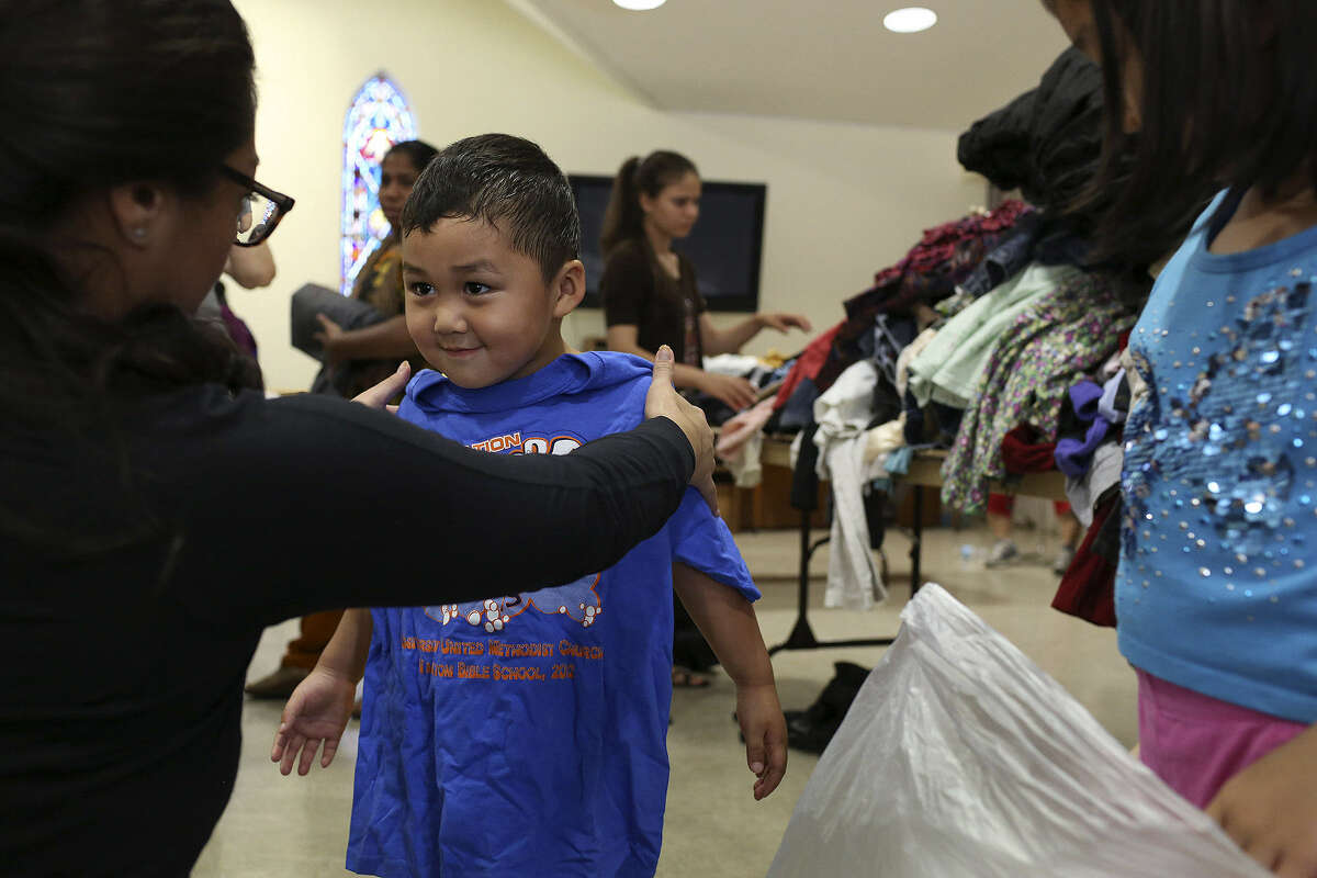 Daniela de León (left), a member of the Bexar County Young Tejano Democrats, helps Jonathan Kae, 3, a refugee from Burma, find clothes to take home during the group's recent Refugee Assistance Day.