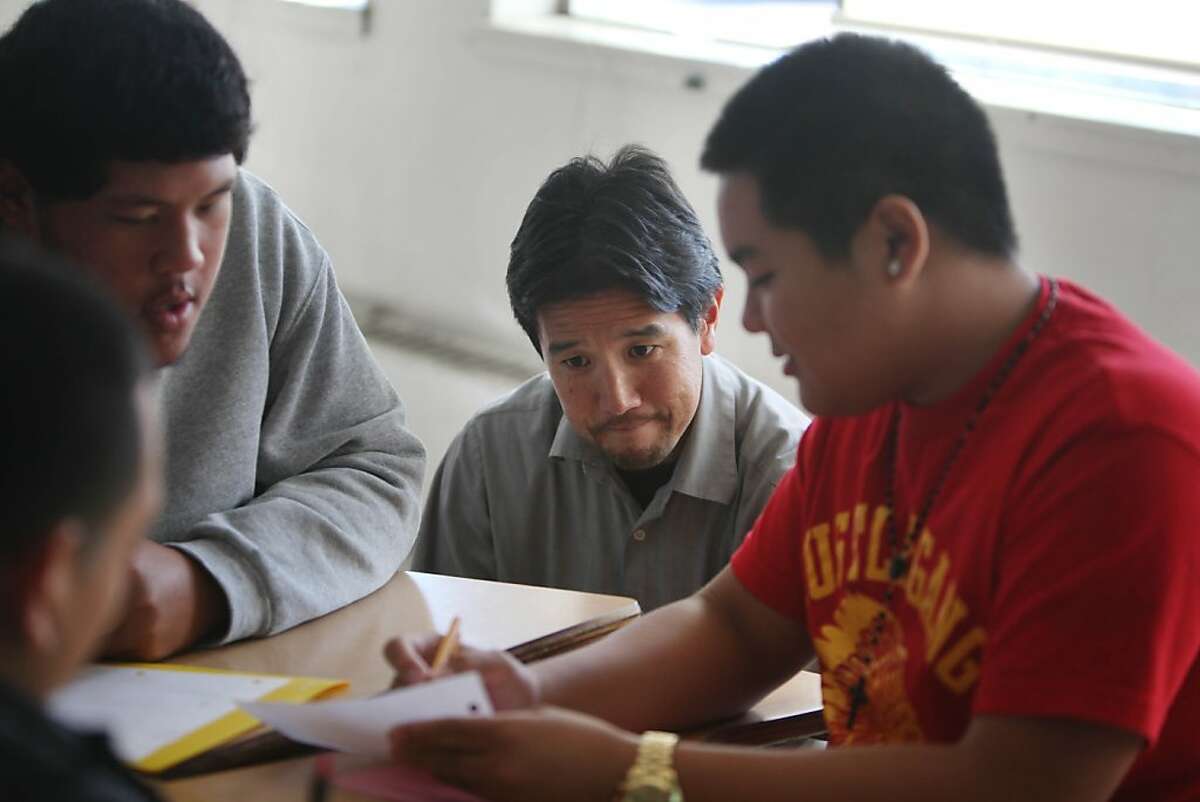 Math instructor Dan Yamamoto (second from right), discusses class work with Juan Carlos Garcia (left), 16; Francis Sosoatu (second from left) and Ryan Sacdalan (right) during an Algebra II class at Phillip and Sala Burton Academic High School on Wednesday, October 2, 2013 in San Francisco, Calif.