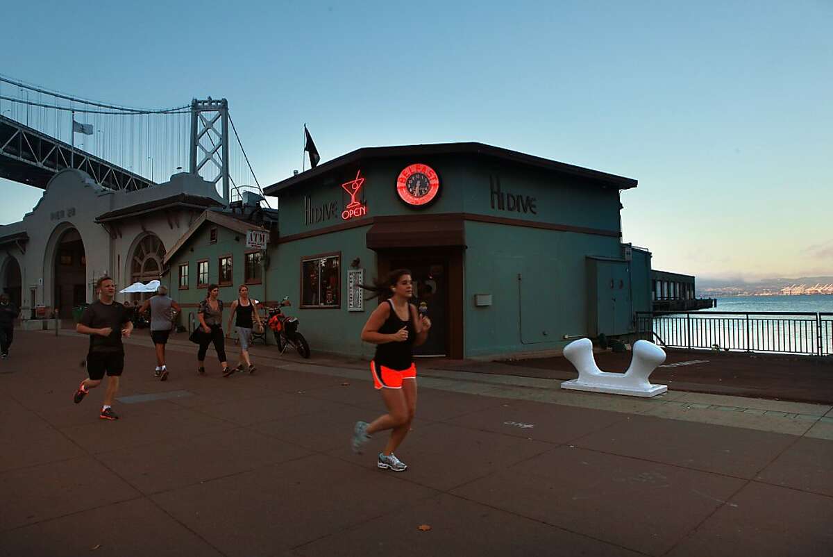 Runners pass by Hi Dive in San Francisco, California, on Wednesday, October 2, 2013.
