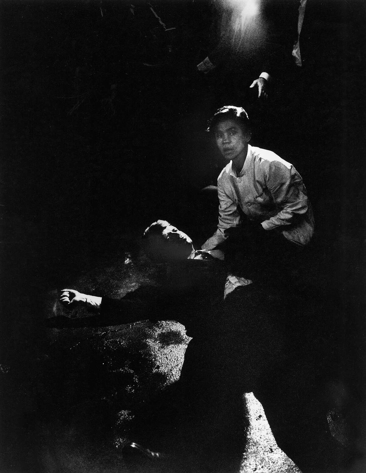 Senator Robert Kennedy sprawled semiconscious in his own blood on floor after being shot in the brain & neck while busboy Juan Romero tries to comfort him, in kitchen at hotel.