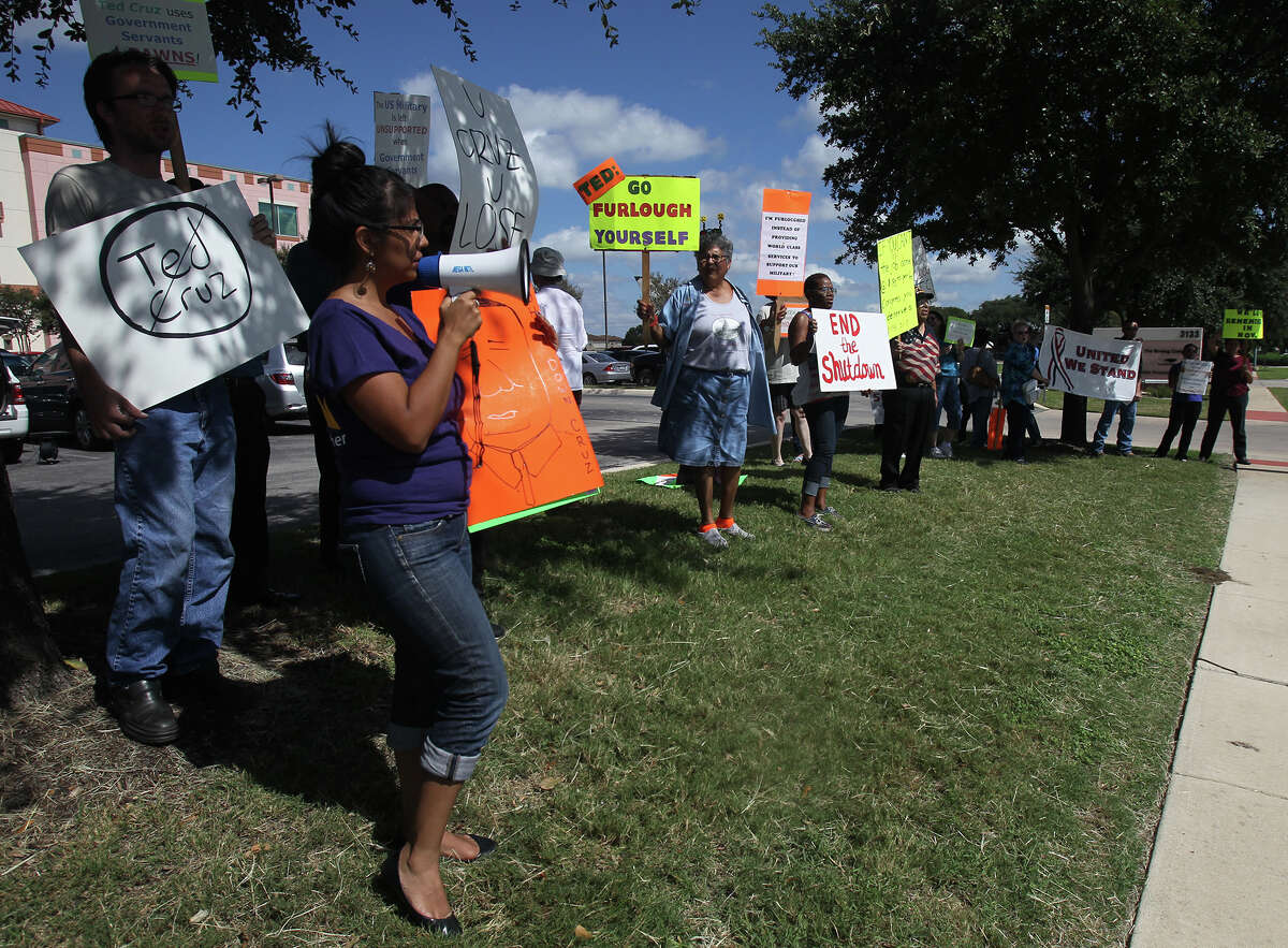 Union worker Marisa Gonzalez (left, holding bullhorn) chants during a demonstration Thursday October 3, 2013 in front of U.S. Senator Ted Cruz's office at Port San Antonio. Federal workers, union members and others gathered in front of and inside of a building there that houses Cruz's office to express their disapproval of Cruz and the recent government shutdown.
