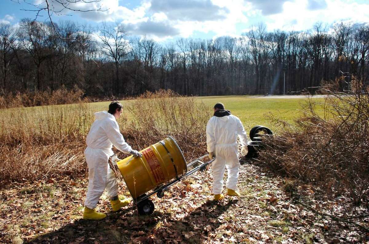 Two workers from Environmental Services, Inc., of South Windsor, CT, neither of whom would give their name, cart away a safety drum which contains an old drum which was discovered on the property of Scofield Magnet Middle School, Tuesday Jan. 26th, 2010.
