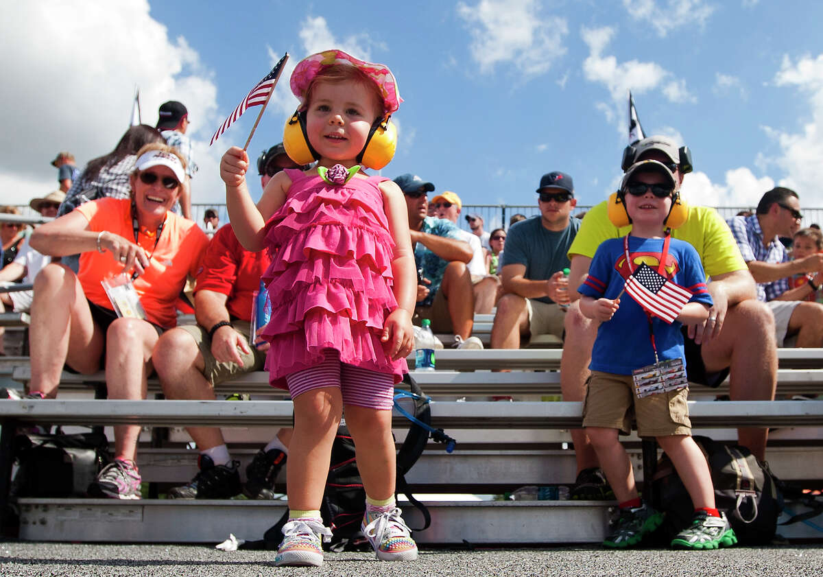 Madeline Bird, 2, holds an American flag as she waits for the start of race one of the Grand Prix Houston on Friday at Reliant Park.