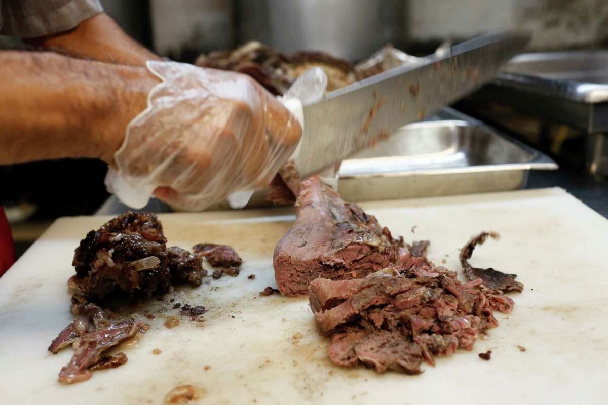 Manuel Martinez carves barbacoa from a cow's head at the shop on Patton where his boss, Jose Luis Lopez, has been cooking for 36 years.