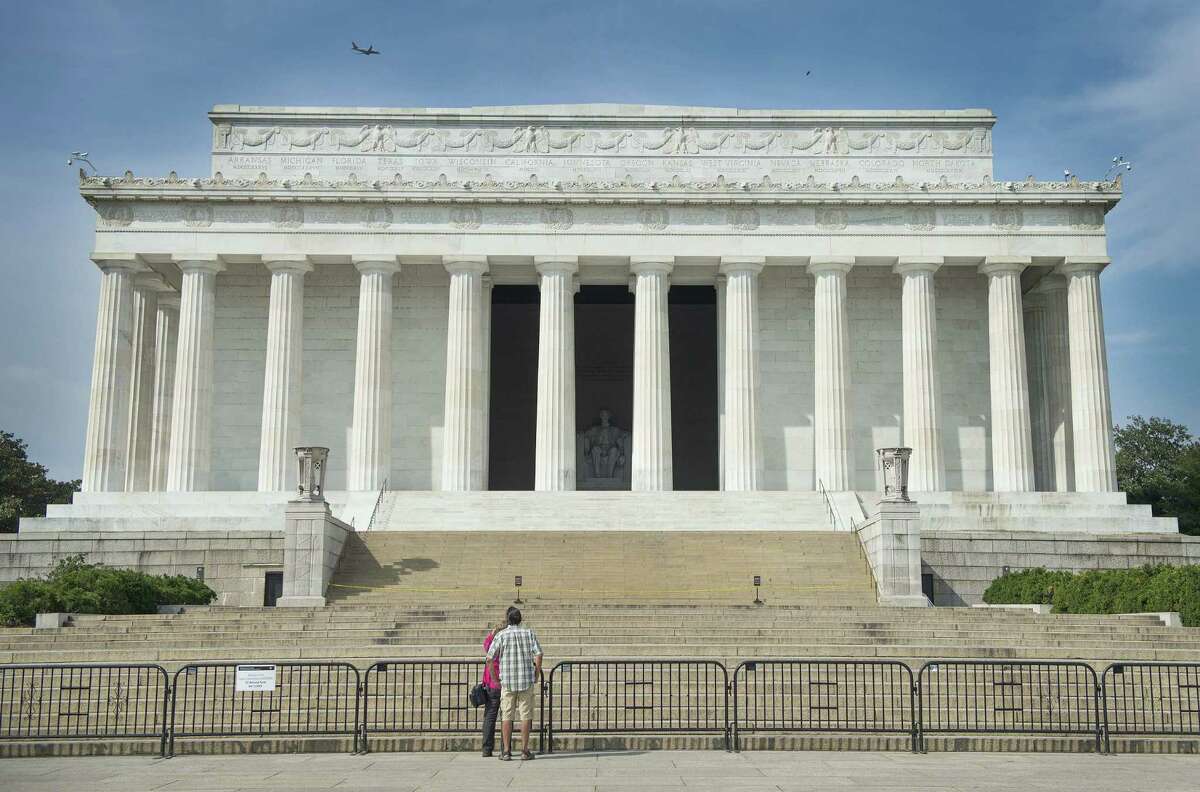 A couple stand  in front of the closed Lincoln Memorial in Washington. A reader blames the shutdown on the inability of both sides to find common ground for compromise.