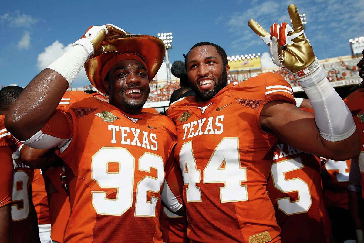DALLAS, TX - OCTOBER 12: (L-R) Reggie Wilson #92 of the Texas Longhorns and Jackson Jeffcoat #44 of the Texas Longhorns celebrate with the game trophy after the Longhorns beat the Sooners 36-20 at the Cotton Bowl on October 12, 2013 in Dallas, Texas.