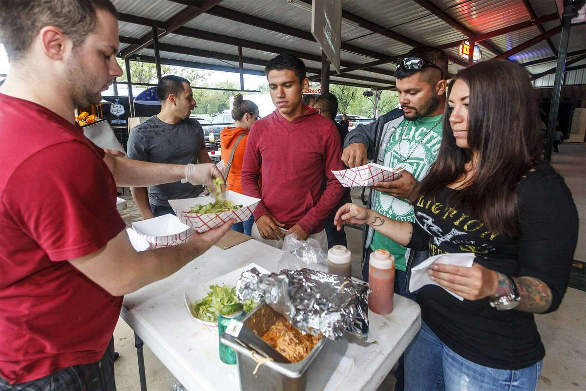 Michael Heinz prepares nachos for (from left) David Castillo, Clarence McFarland and Christina McFarland at the Barbacoa & Big Red Fall Festival at the R&J Music Pavilion in south Bexar County.