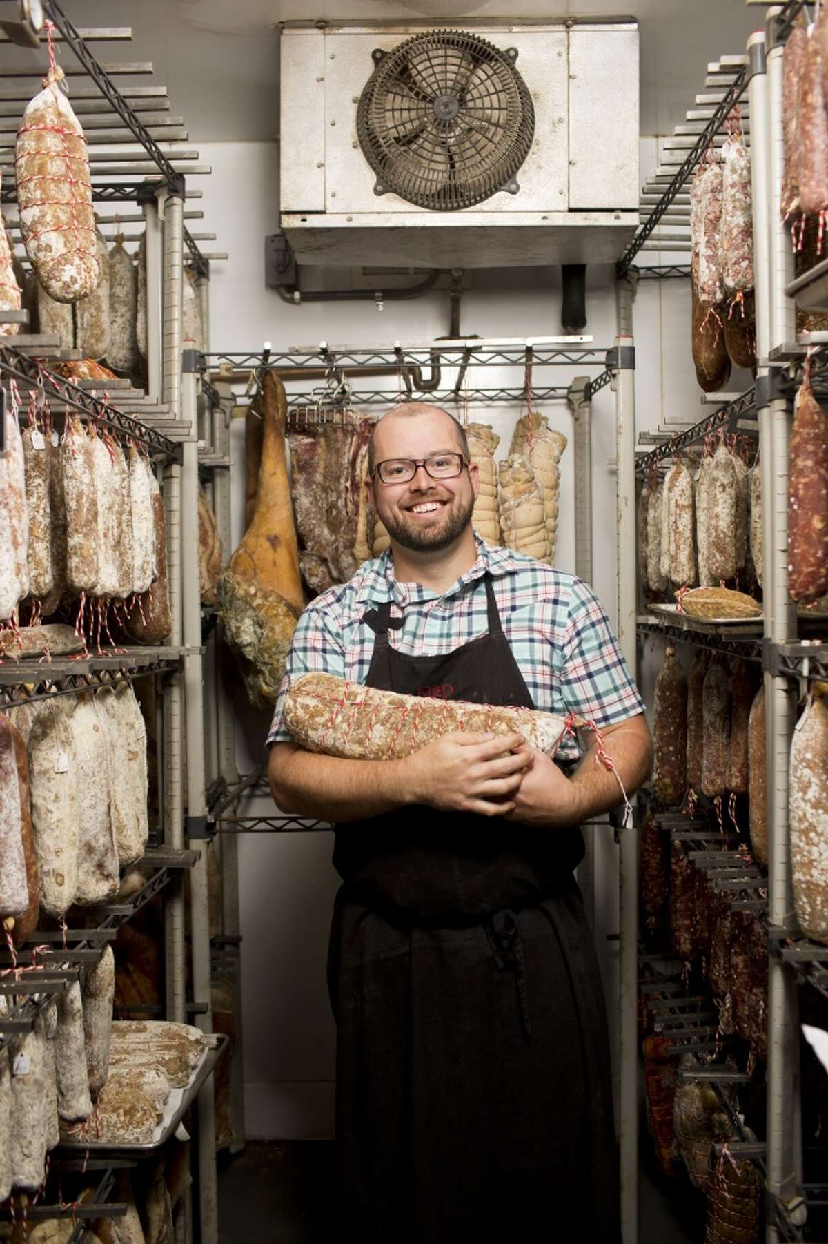 Ryan Harris of Fatted Calf cradles meat in the curing room.
