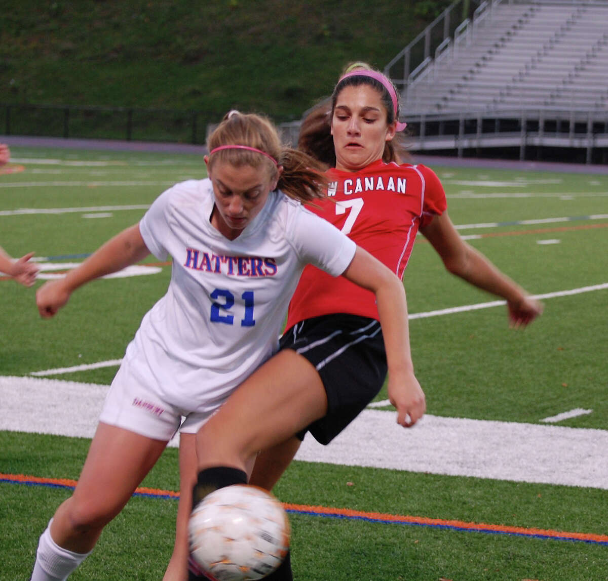 New Canaan's Azada Amis-Aslani (No. 7) and Danbury's Charlotte Blain (No. 21) get tangled up going for the ball during Danburyís 2-1 win at Danbury High School on Monday, Oct. 14, 2013. Contributed photo by Kim Persky.