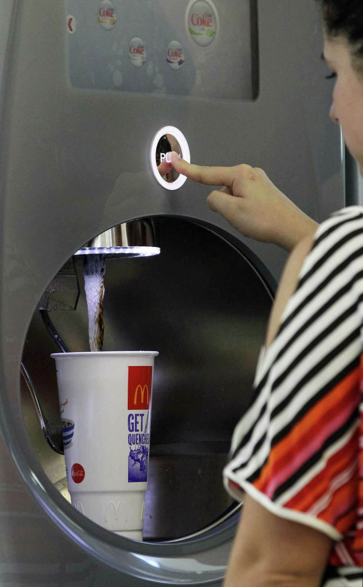 Christina Nunez fills a cup at a fast-food restaurant in New York. Nationally, more than half of front-line fast-food workers' families use at least one public assistance program.