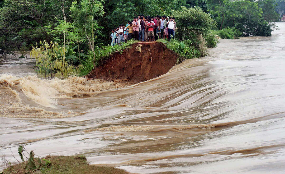 Indian villagers stand on the breached embankment of swollen Kangsabati river at Samat village in West Bengal state, India, Tuesday, Oct. 15, 2013. Heavy torrential rain in the aftermath of weekend Cyclone Phailin have made rivers to overflow causing flood situation in the state.
