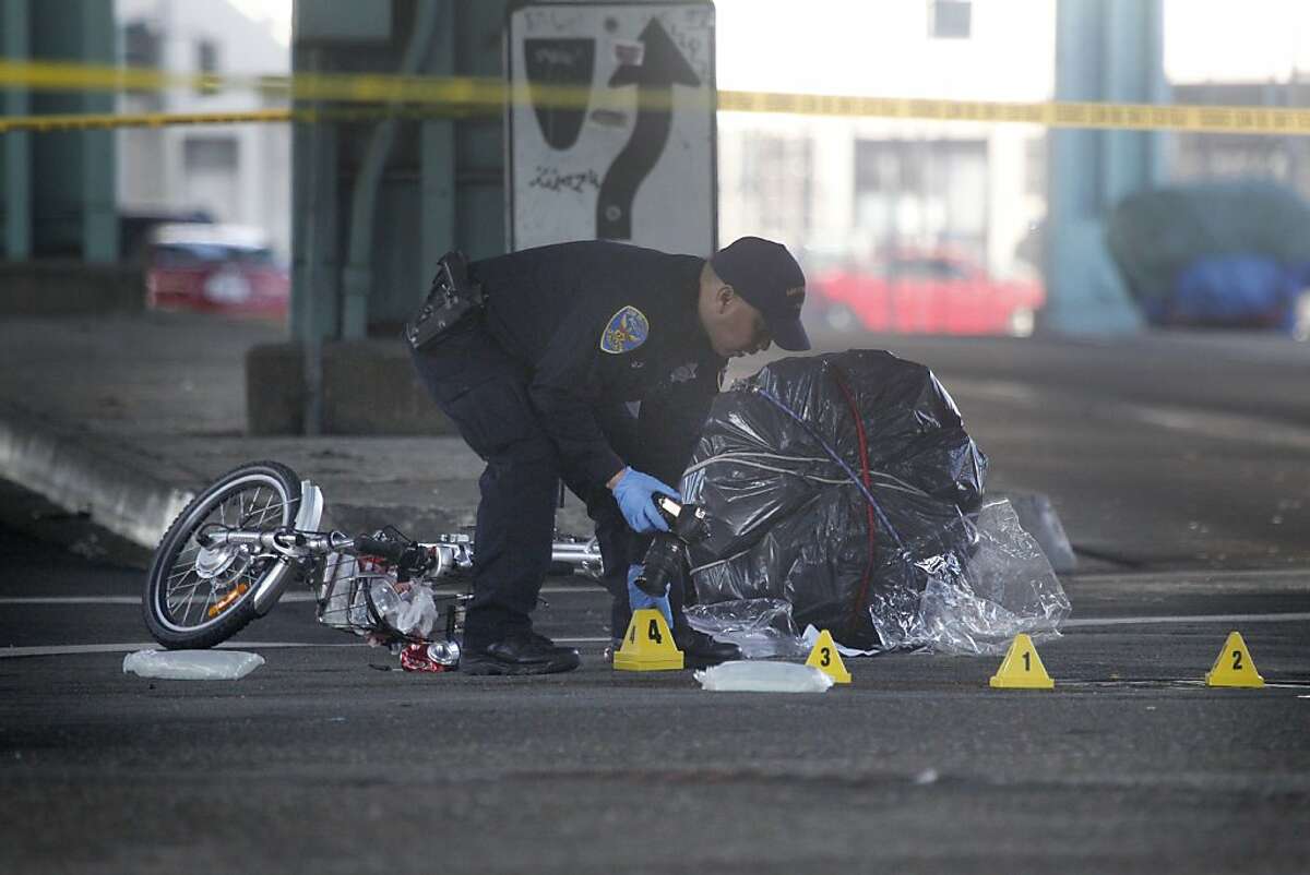 An SFPD officer takes photos while working at the scene where a bicyclist was killed Friday morning in a collision with a Muni bus on Friday, October 18, 2013 in San Francisco, Calif.