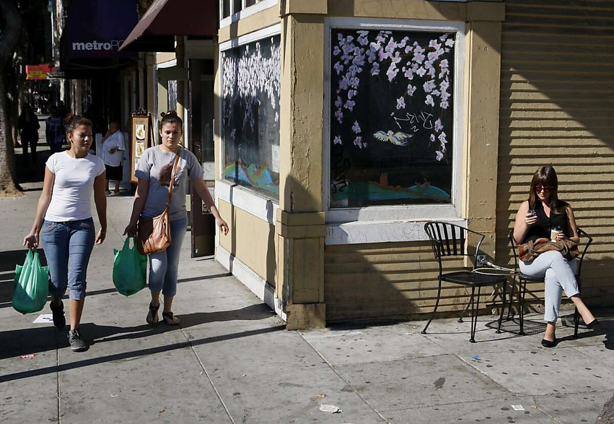 Lucy Rodriguez, left, and Yorleny Juarez walk down 24th st with groceries while Samantha Bell drinks coffee outside of Bello Coffee on 24th st in San Francisco, Calif. on Friday, Oct. 18, 2013.