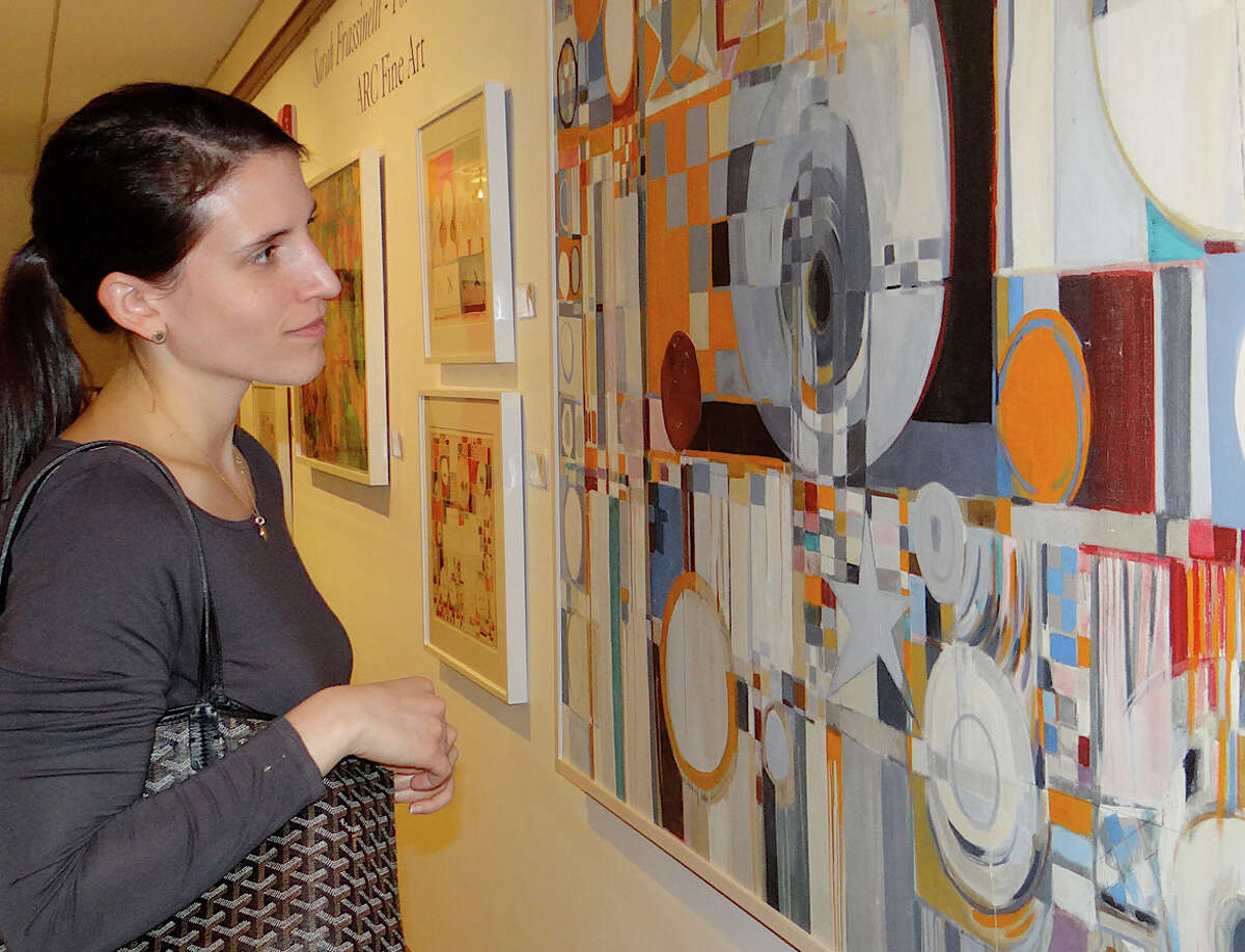 Elinor Garcia of Fairfield examines Sarah Frassinelli's "Circles & Stars" at Friday's preview of the Pequot Library's 16th annual Art Show.