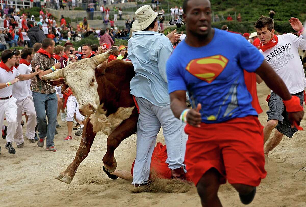 Participants are knocked over by charging bulls during the Great Bull Run at the Georgia International Horse Park, Saturday, Oct. 19, 2013, in Conyers, Ga.