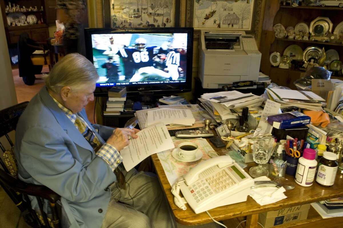 Bud Adams looks over papers while watching football on television at his home in 2009.