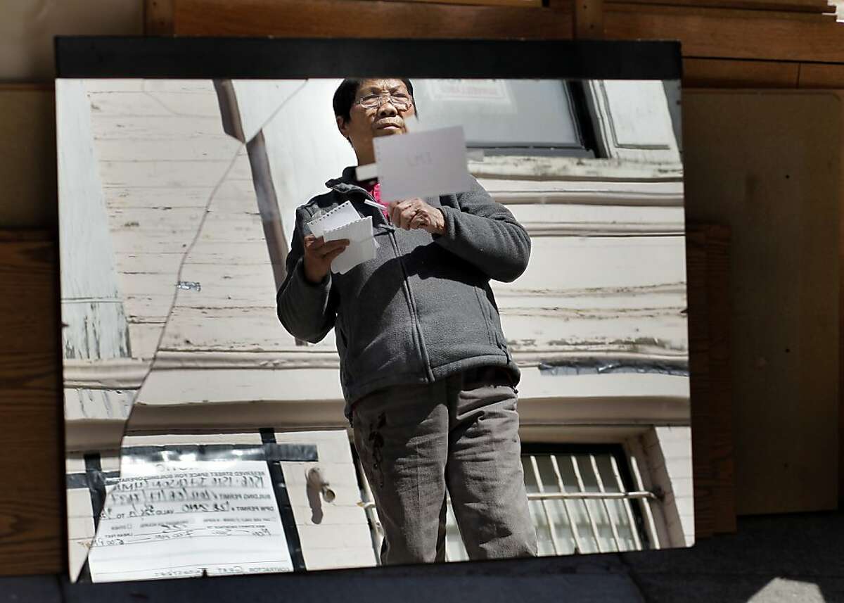 Gum Gee Lee is reflected in a broken mirror brought down from the home recently in San Francisco. The Lee family, who are being evicted from their San Francisco home of over 30 years, move some belongings to the street for pick up.