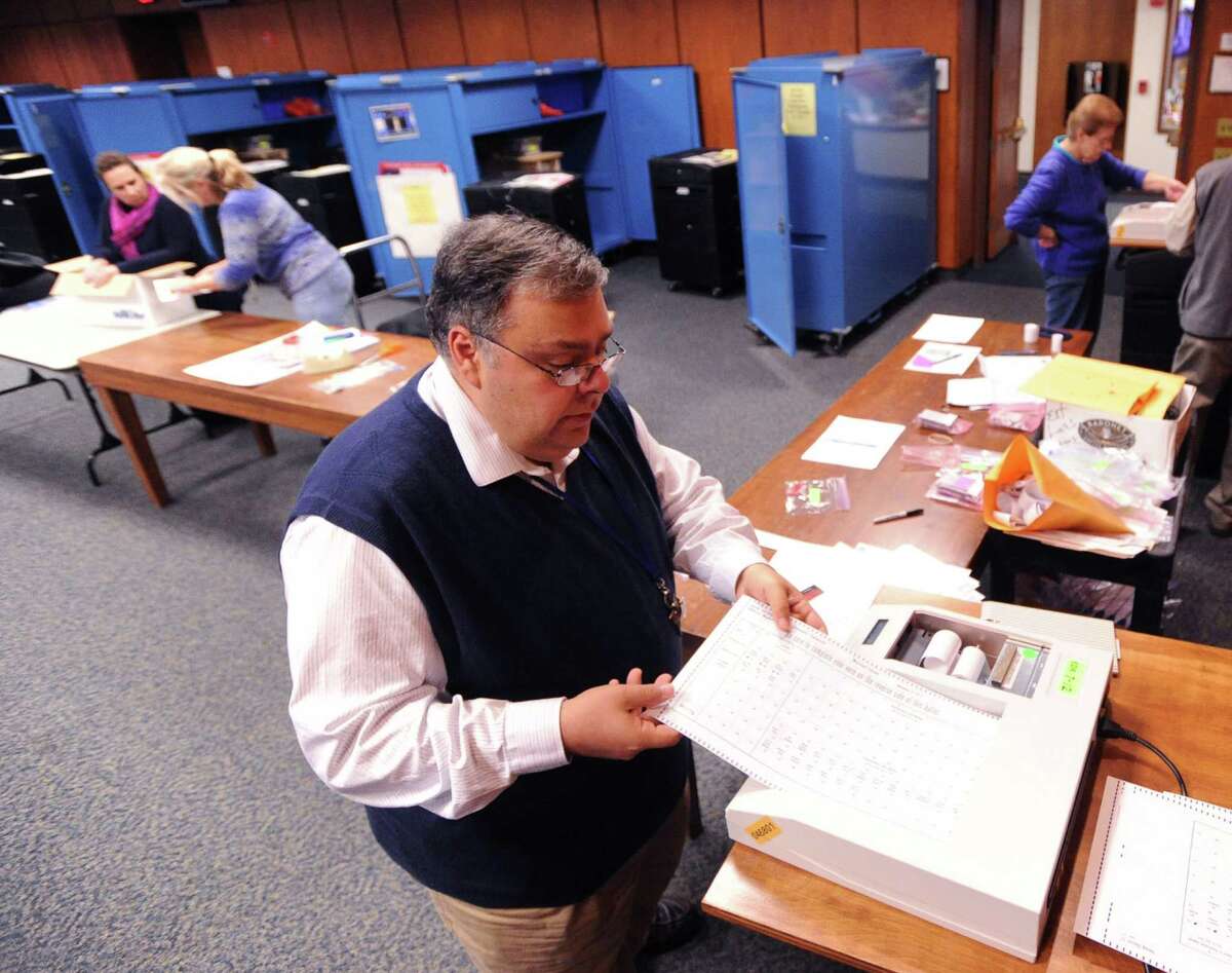 At center, Registrar of Voters, Fred DeCaro, a republican, runs a test on an election tabulator in the meeting room at Greenwich Town Hall, Thursday, Oct. 24, 2013, as part of the preparation for the upcoming election on Tuesday, Nov. 5.