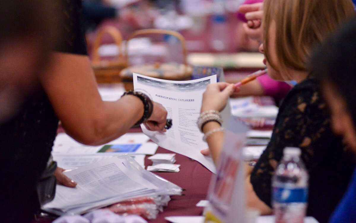 People look over a list of employers participating in the job fair. USAA sponsored the event.