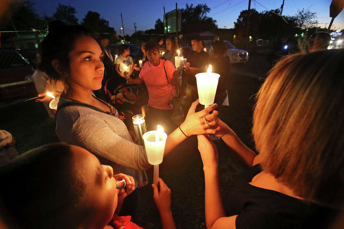 Abby Faz (left) steadies a candle for Valerie Guzman as Raymond Cano watches as supporters gather with family members on October 24, 2013 in the 3900 block of Culebra to hold a candle light vigil and prayer for Sharon Ledesma who was hit by a car Wednesday morning as she crossed Culebra.
