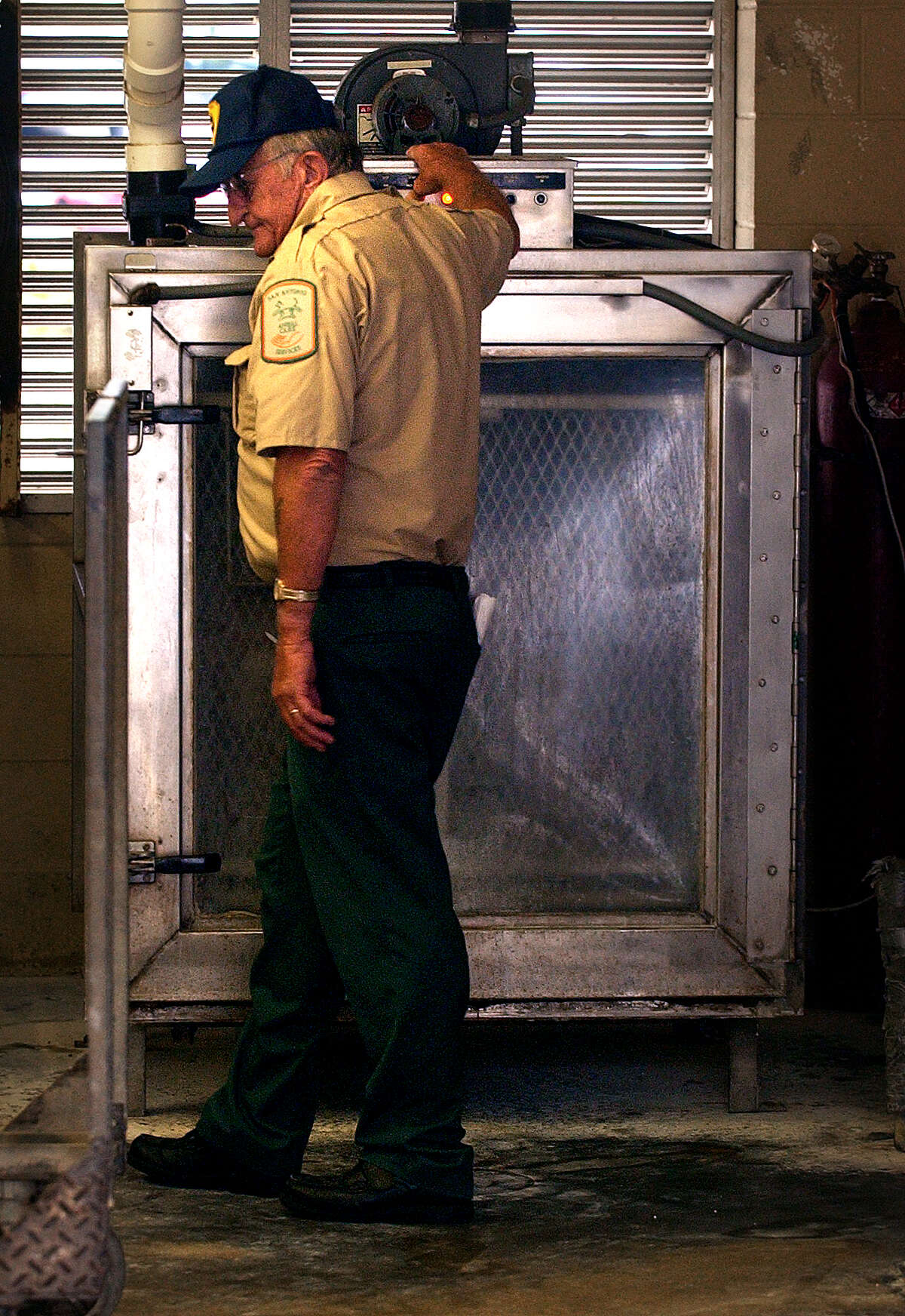 David Lee Nichols of the Animal Care and Control Department on Tuleta, pushes a button to start the gasing process to euthanize a cage of dogs, Saturday, June 12, 2004. photo Bob Owen
